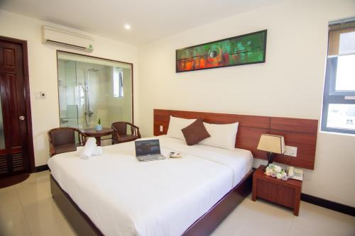 a bedroom with a bed with a laptop on it at Quoc Cuong Hotel & Apartment Danang by Haviland in Da Nang