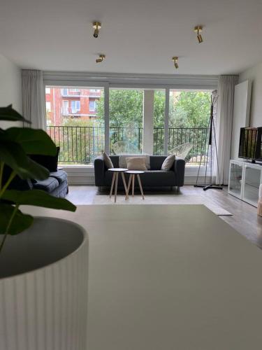 a living room with a couch and a large window at Recent en lichtrijk duplex-appartement te Wenduine in Wenduine