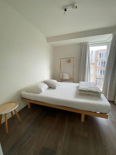 a large bed in a room with a window at Recent en lichtrijk duplex-appartement te Wenduine in Wenduine