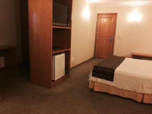 a hotel room with a bed and a flat screen tv at Barbur Plaza Hotel in Ponta Grossa