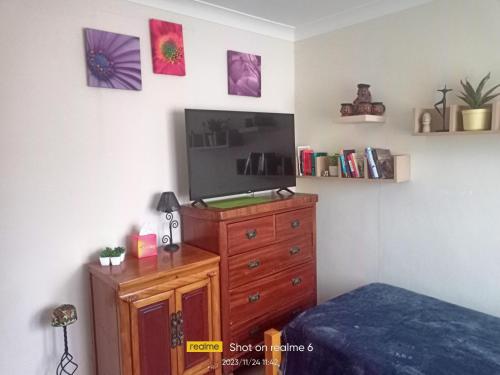 a bedroom with a bed and a dresser and a tv at Goldy's place in E17 in London