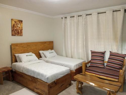 sypialnia z 2 łóżkami, krzesłem i oknem w obiekcie INFINITE GREEN EVENTS GARDEN AND ACCOMMODATION w mieście Dowsonville