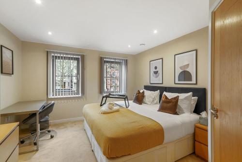 a bedroom with a large bed with a desk and windows at LiveStay-Stunning 2 Bed 2 Bath Apartment in Maida Vale in London