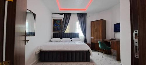 a bedroom with a bed and a green chair at De Miami Park Suites & Bar in Owerri