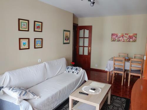 ein Wohnzimmer mit einem weißen Sofa und einem Tisch in der Unterkunft Cuenca 3 in Gijón
