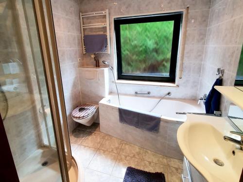 ein Bad mit einer Badewanne, einem Waschbecken und einem Fenster in der Unterkunft Cozy Apartments in Limeshain in Hainchen
