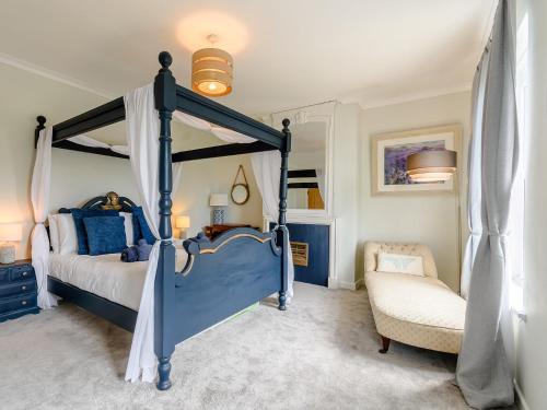 a bedroom with a blue canopy bed and a chair at 4 Bed in Bexhill on Sea 77602 in Bexhill