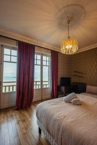 une chambre avec un grand lit et un lustre dans l'établissement Villa Ellerslie, à Saint-Malo