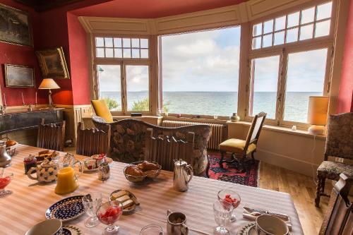 una sala da pranzo con tavolo e vista sull'oceano di Villa Ellerslie a Saint Malo