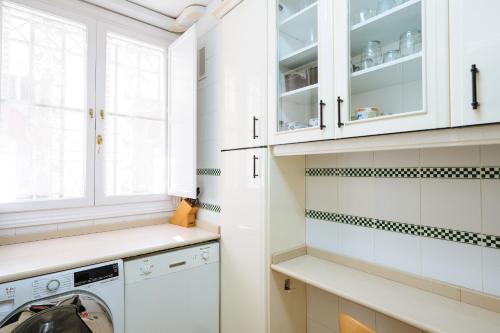 pralnia z białymi szafkami, pralką i suszarką w obiekcie APARTAMENTO EN CASA PALACIO CON PISCINA 15 MAYO a 15 OCTUBRE w Sewilli