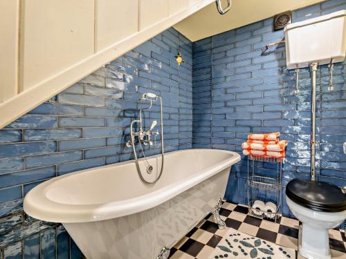 a blue bathroom with a tub and a toilet at 1 Bed in Robin Hoods Bay G0191 in Fylingdales
