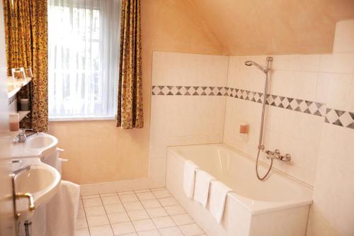Baño blanco con bañera y lavamanos en Landgasthof & Hotel Jagdhof, en Stralsund