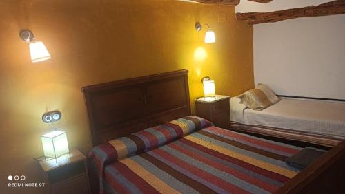 1 dormitorio pequeño con 1 cama y 2 lámparas en L'Antic Forn de Paüls, en Paüls