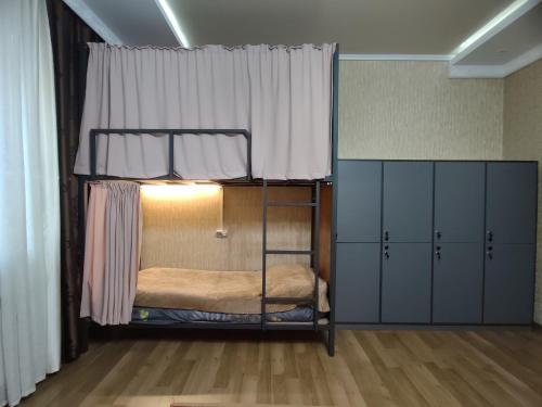 a room with a bunk bed with a window and cabinets at Archa Hostel in Bishkek