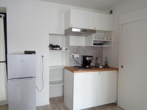 une cuisine avec des armoires blanches et un réfrigérateur blanc dans l'établissement Appartement à 50m de la plage, à Saint-Michel-en-Grève