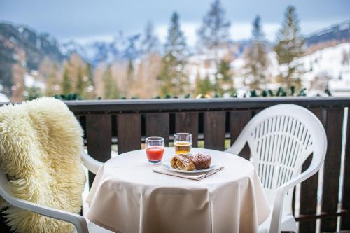 a table with two glasses of wine and a plate of food at Hotel Nigritella in Selva di Cadore