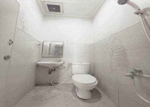 ein weißes Bad mit einem WC und einem Waschbecken in der Unterkunft OYO 93500 Rizki Residence TOS Syariah in Jakarta