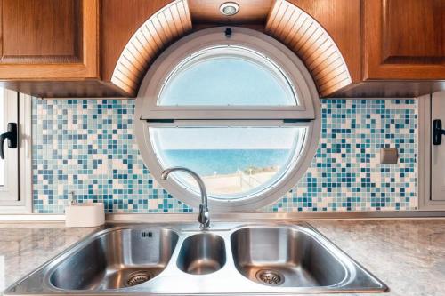 a kitchen with a sink and a window with the ocean at Blue Pearl Apolakkia in Apolakkiá