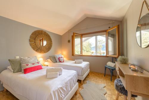 聖若里奧的住宿－La Villa des Pecheurs, Maison de Famille avec vue imprenable - LLA Selections by Location lac Annecy，一间卧室设有两张床、一张桌子和窗户。