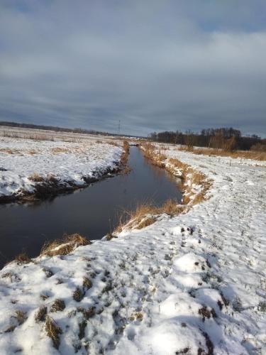 a river in a field covered in snow at Agroturystyka na Łubii in Miastkowo