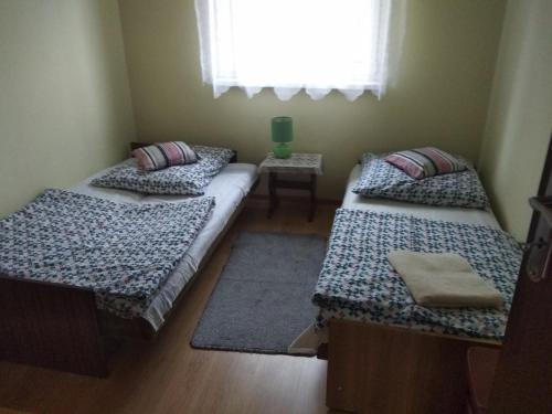 two beds in a small room with a window at Agroturystyka na Łubii in Miastkowo