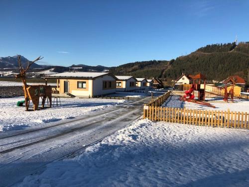eine schneebedeckte Straße mit Häusern und einem Zaun in der Unterkunft Rezort Zvernica Vlachy in Vlachy