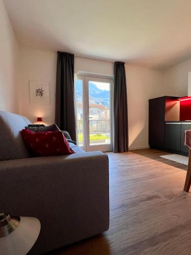 a living room with a couch and a sliding glass door at CASA VACANZE LA BRENTA in Chiavenna