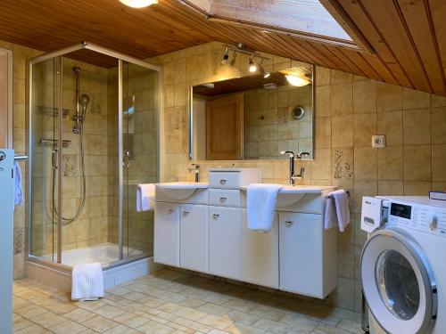 ein Badezimmer mit 2 Waschbecken, einer Dusche und einer Waschmaschine in der Unterkunft das Landblick in Sillian