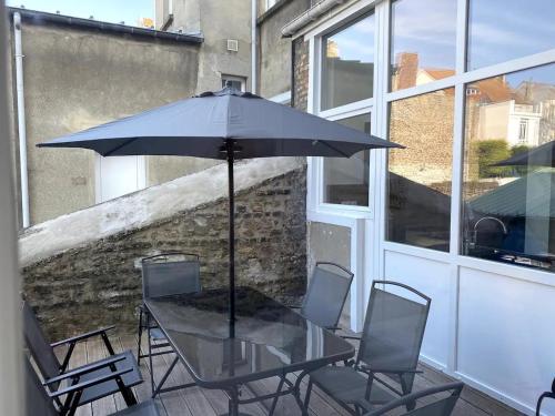 una mesa de cristal con sillas y una sombrilla en el balcón en Cocooning 1 Conciergerie Leroy en Boulogne-sur-Mer