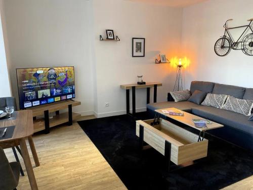 sala de estar con sofá azul y TV de pantalla plana en Cocooning 1 Conciergerie Leroy en Boulogne-sur-Mer