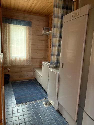 Elle comprend une petite cuisine avec un réfrigérateur et une fenêtre. dans l'établissement Hostel Lomakivi, à Kausala