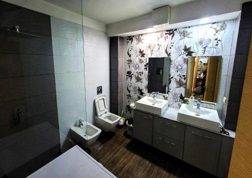 ein Badezimmer mit zwei Waschbecken, einem WC und einem Spiegel in der Unterkunft Spacious and Cozy Apartment in Tirana
