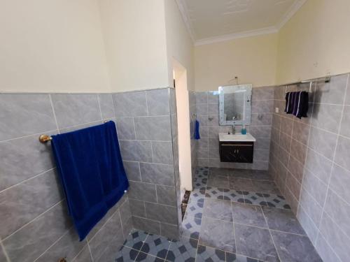 a bathroom with a shower with a blue towel at Diamond Sands Villa in Ukunda