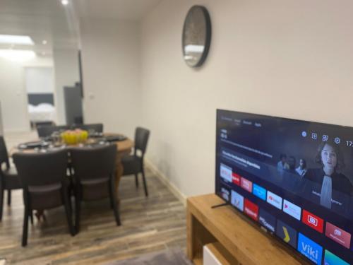 un salon avec une télévision et une table avec des chaises dans l'établissement Bienvenue au Ptit T'Anaïs,, à Boulogne-sur-Mer