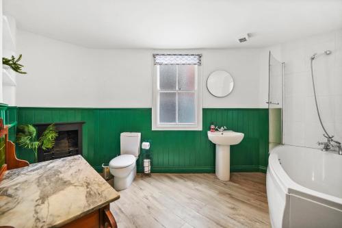 uma casa de banho verde com uma banheira, um WC e um lavatório. em Harbourside Heaven in Bristol - Sleeps 8 em Bristol