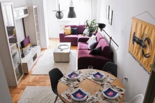 sala de estar con mesa y sofá púrpura en La Maison, en Niš