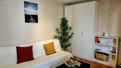 a living room with a white couch and a plant at Tranquillité in Vincennes
