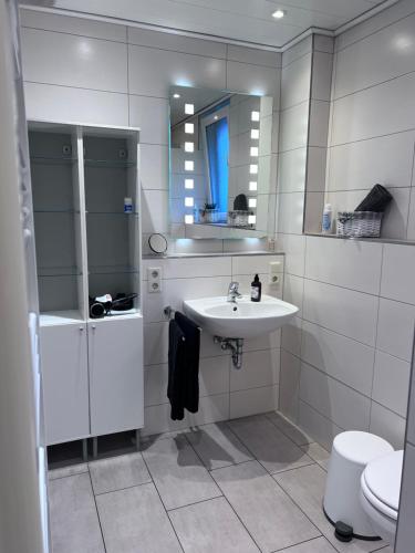 a bathroom with a sink and a toilet and a mirror at Allee zum See in Schüttorf