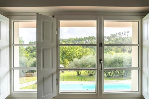 une fenêtre ouverte avec vue sur une piscine vue à travers elle dans l'établissement Villa Oliviana, à Montecarlo