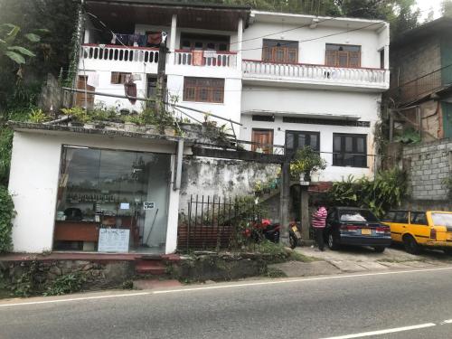 un edificio blanco con un hombre parado frente a él en Kandy Mount View hotel en Peradeniya