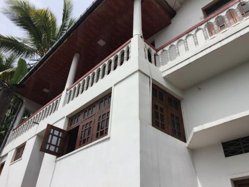 a white house with wooden doors and a palm tree at Kandy Mount View hotel in Peradeniya