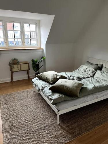 a bed with pillows on it in a room at Lys nyrenoveret lejlighed i Odense C in Odense