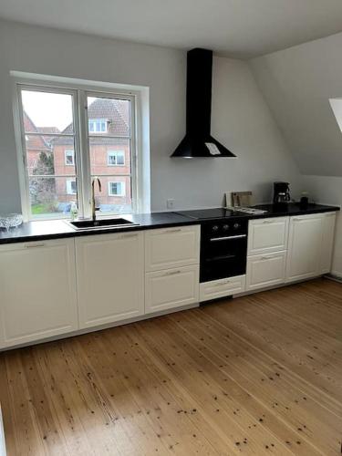 a kitchen with white cabinets and a black counter top at Lys nyrenoveret lejlighed i Odense C in Odense
