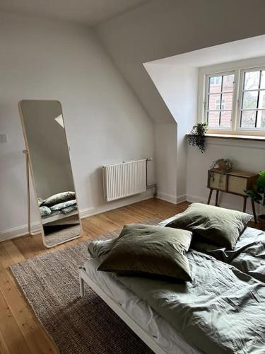 1 dormitorio con 1 cama grande y espejo en Lys nyrenoveret lejlighed i Odense C, en Odense