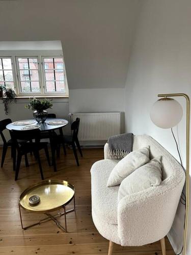 sala de estar con silla y mesa en Lys nyrenoveret lejlighed i Odense C, en Odense