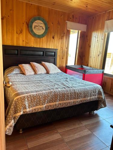 een slaapkamer met een bed met een houten muur bij Cabaña en chovellen in Pelluhue