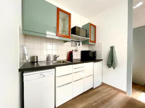 une cuisine avec des armoires blanches et un comptoir noir dans l'établissement Capitole, Grand T1 bis, lumineux, neuf., à Toulouse