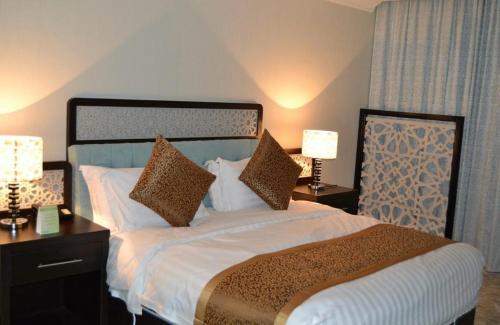 a bedroom with a bed with two lamps and two tables at Cozy studio Minutes to Cornich & Bahrain bridge in Al Khobar