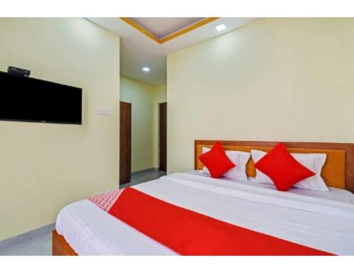 um quarto com uma cama com almofadas vermelhas e uma televisão em Hotel Om Shanti Palace, Kolkata em Calcutá