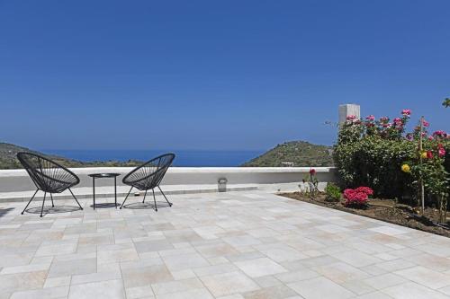 two chairs and a table on a patio overlooking the ocean at Icaria Great Filling House in Évdhilos
